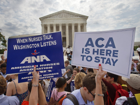 Supporters of the Affordable Care Act hold up signs as the opinion for health care is reported outside of the Supreme Court in Washington, Thursday June 25, 2015 (Credit: AP Photo/Jacquelyn Martin)