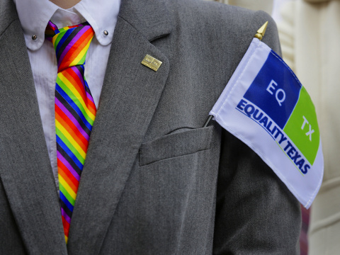 A person wearing a rainbow-colored tie and Equality Texas flag joins faith leaders and congregation members of various churches from around the state rally on the step of the Texas Capitol steps to call for more equality for same-sex couples, Tuesday, February 17, 2015, in Austin, Texas (Credit: AP Photo/Eric Gay)