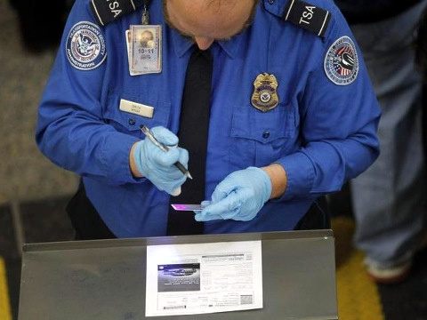 A Transportation Security Administration (TSA) agent uses a special light to check the authenticity of a traveller's driver's license at Ronald Reagan Washington National Airport in Washington November 24, 2010 (Credit: Reuters/Jason Reed)