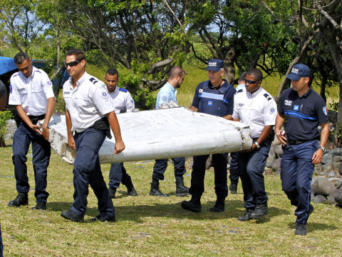 French police officers carry a piece of debris from a plane in Saint-Andre, Reunion Island, which air safety investigators, one of them a Boeing investigator, have identified the component as a flaperon from the trailing edge of a Boeing 777 wing, a U.S. official said, July 29, 2015 (Credit: AP Photo/Lucas Marie)