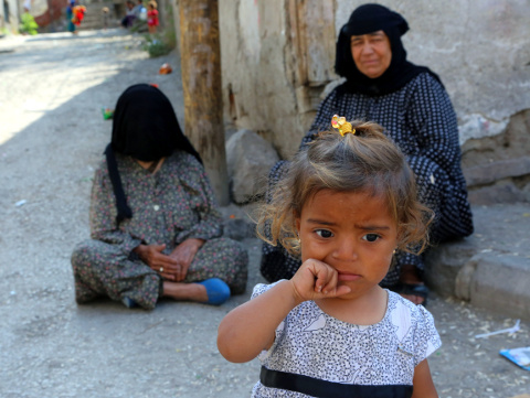 Syrian refugees sit in front of a derelict building in Haci Bayram neighborhood in Ankara, Turkey, July 27, 2015 (Credit: AP Photo/Burhan Ozbilici)