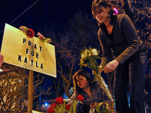 Isabella Nalda, bottom, and her mother, Eileen, place flowers at a makeshift memorial for Kayla Mueller, a 26-year-old American woman who was kidnapped, brutalized, raped and killed by Abu Bakr al-Baghdadi, leader of ISIS, Prescott, Arizona, February 10, 2015 (Credit: AP Photo/The Daily Courier/Matt Hinshaw)