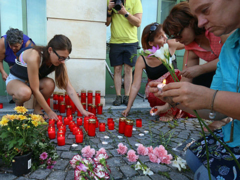 People light candles in front of the police station in Eisenstadt, Austria, to memorialize the death of at least 20, possibly over 70, migrants stacked in a truck parked on the shoulder of the main highway from Budapest to Vienna near Eisenstadt, August 27, 2015 (Credit: AP Photo/Ronald Zak)