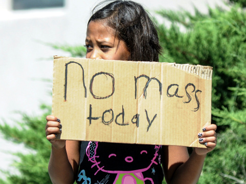 A young parishoner stands on N Alameda Boulevard holding a sign advising parishoners that Holy Cross Catholic Church mass is canceled after two churches in Las Cruces, New Mexico were bombed less than 30 minutes apart, Las Cruces, NM, August 2, 2015 (Credit: AP/The Las Cruces Sun-News/Robin Zielinski)