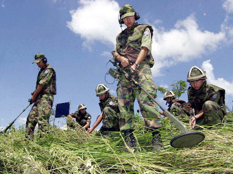 South Korean Army soldiers search for landmines possibly washed away by torrential rains from the demilitarized zone between the two Koreas, into a rice field in Yeoncheon, north of Seoul, South Korea, August 8, 2002 (Credit: AP Photo/Yonhap)