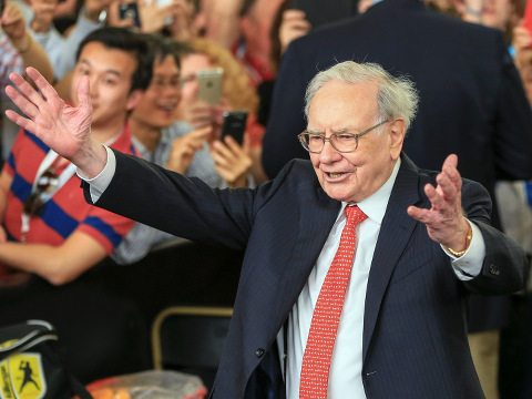 Berkshire Hathaway Chairman and CEO Warren Buffett lifts his arms to greet table tennis prodigy Ariel Hsing, unseen, before briefly playing some table tennis outside the Borsheims jewelry store, a Berkshire Hathaway subsidiary, in Omaha, Nebraska, May 3, 2015 (Credit: AP Photo/Nati Harnik)