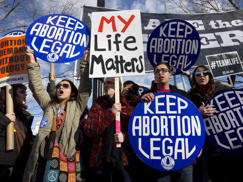 Pro-abortion rights counter protesters hold signs while anti-abortion demonstrators march past the Supreme Court in during the annual March for Life, protesting the Supreme Court's landmark 1973 decision that declared a constitutional right to abortion, Washington, January 22, 2015 (AP Photo/Jacquelyn Martin)