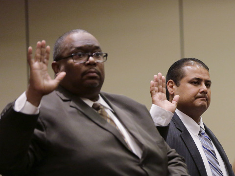Jay High School head football coach Gary Gutierrez, center, and principal Robert Harris, left, are sworn in at a University Interscholastic League (UIL) State Executive Committee, where they reported that they believed that assistant coach Mack Breed told players to retaliate against an official in the closing minutes of a game earlier this month, Round Rock, Texas, September 24, 2015 (Credit: AP Photo/Eric Gay)
