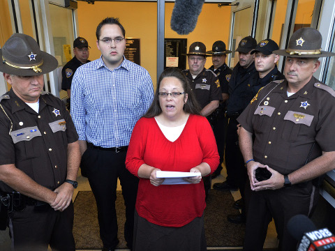 Surrounded by Rowan County Sheriff's deputies, Rowan County Clerk Kim Davis, center, with her son Nathan Davis standing by her side, makes a statement to the media at the front door of the Rowan County Judicial Center in Morehead, Kentucky, Monday, September 14, 2015 (Credit: AP Photo/Timothy D. Easley)