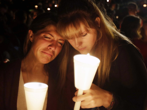 Kristen Sterner, left, and Carrissa Welding, both students at Umpqua Community College, embrace each other during a candlelight vigil for those killed during a shooting at the college, Roseburg, Oregon, October 1, 2015 (Credit: AP Photo/Rich Pedroncelli)
