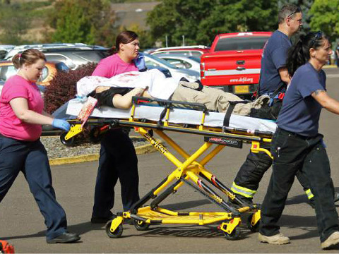 Authorities carry a shooting victim away from the scene after a gunman opened fire at Umpqua Community College in Roseburg, Oregon, October 1, 2015 (Credit: AP/Roseburg News-Review/Mike Sullivan)
