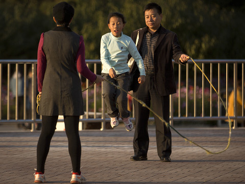 A man and woman twirl a jump rope for a girl at a park in Beijing, October 31, 2015 (Credit: AP Photo/Mark Schiefelbein)