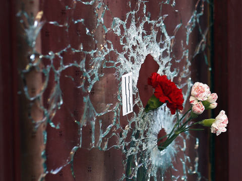 Flowers are set in a window shattered by a bullet at the Carillon cafe in Paris, France, two days after over 120 people were killed in a series of shooting and explosions while French troops deployed around Paris on Sunday and tourist sites stood shuttered in one of the most visited cities on Earth while investigators questioned the relatives of a suspected suicide bomber involved in the country's deadliest violence since World War II. (Credit: AP Photo/Jerome Delay)