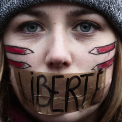 A woman has taped her mouth displaying the word Freedom on the tape as she gathers with several thousand people in solidarity with victims of two terrorist attacks in Paris, one at the office of weekly newspaper Charlie Hebdo and another at a kosher market, in front of the Brandenburg Gate near the French embassy in Berlin, January 11, 2015 (Credit: AP Photo/Markus Schreiber)