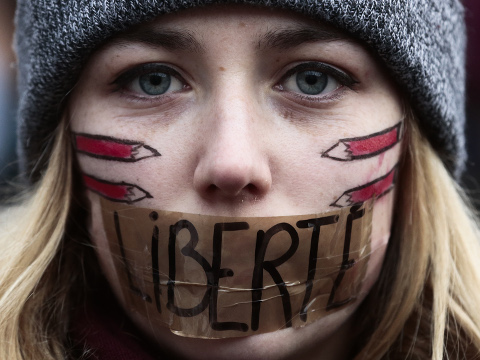 A woman has taped her mouth displaying the word Freedom on the tape as she gathers with several thousand people in solidarity with victims of two terrorist attacks in Paris, one at the office of weekly newspaper Charlie Hebdo and another at a kosher market, in front of the Brandenburg Gate near the French embassy in Berlin, January 11, 2015 (Credit: AP Photo/Markus Schreiber)