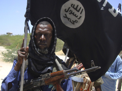 An elderly man from a Somali tribal clan carries an AK-47 and the Islamist black flag with the words 'There is no God but Allah and Mohamed Is the Prophet of Allah' as he vows to fight the Somali government forces and African Union peacekeeping troops in Mogadishu's Maslah Square neighborhood, March 5, 2011 (Credit: AP Photo/Farah Abdi Warsameh)