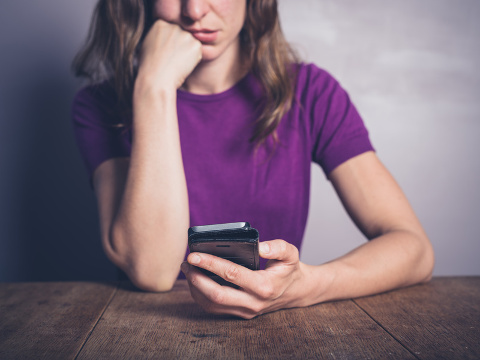 Bored woman using smartphone at table,