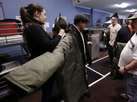 In a Tuesday, March 3, 2015 photo, Veronika Scott of The Empowerment Plan Detroit, helps Todd Frank test wear one of her sleeping bag coats she designed, in Pontiac, Mich. Scott, a former design student is trying to help the homeless population in two distinct ways by employing and training homeless women to manufacture a garment that serves as both a coat and a sleeping bag. The coats then are distributed back to homeless people at no cost to them. (AP Photo/Carlos Osorio)