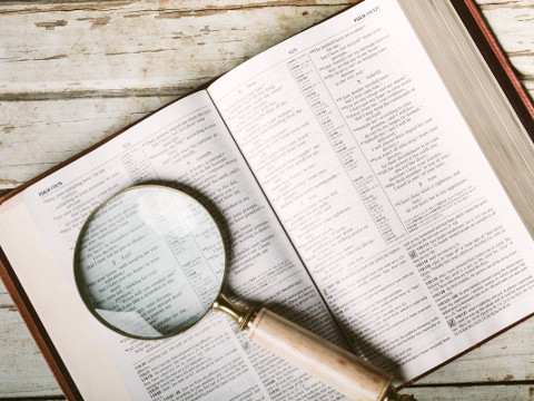 Magnifying glass laying on top of pages of Bible open to Psalm 119 laying on wooden table (Credit: Pearl via Lightstock)