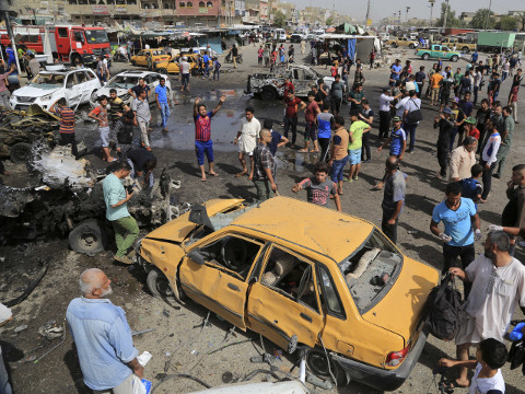 Security forces and citizens inspect the scene after a suicide car bombing hit a crowded outdoor market in Baghdad's eastern Shiite neighborhood of Sadr City, Iraq, Tuesday, May 17, 2016. A wave of bombings struck outdoor markets in Shiite-dominated neighborhoods of Baghdad on Tuesday, killing and wounding dozens of civilians, officials said, the latest in deadly militant attacks far from the front lines in the country's north and west where Iraqi forces are battling the Islamic State group. (AP Photo/Karim Kadim)