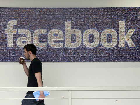 FILE - In this March 15, 2013, file photo, a Facebook employee walks past a sign at Facebook headquarters in Menlo Park, Calif. Facebook reports financial results on Wednesday, April 27, 2016. (AP Photo/Jeff Chiu, File)