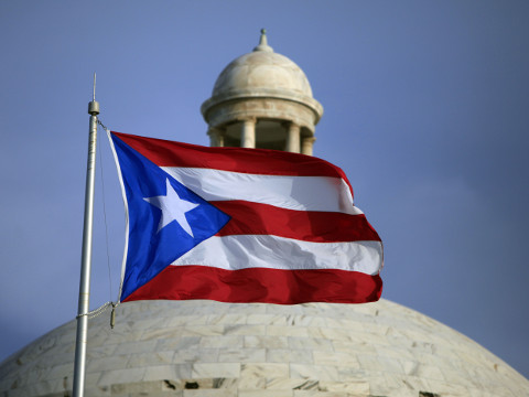 FILE - In this Wednesday, July 29, file 2015 photo, the Puerto Rican flag flies in front of Puerto Rico’s Capitol as in San Juan, Puerto Rico. Puerto Rico Gov. Alejandro Javier Garcia Padilla said on Sunday, May 1, 2016, that negotiators for the U.S. territory’s government have failed to reach a last-minute deal to avoid a third default and that he has issued an executive order to withhold payment. (AP Photo/Ricardo Arduengo, File)