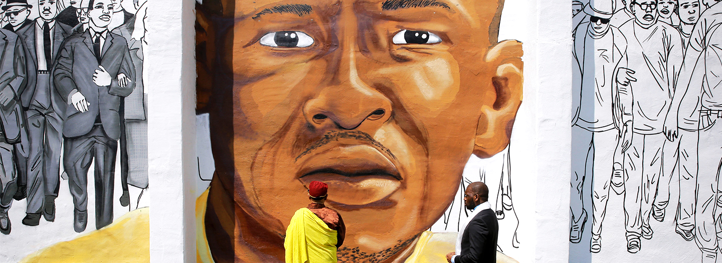 The Gyalwang Drukpa, bottom center, the Buddhist leader of South Asia, prays in front of a mural depicting Freddie Gray alongside the Rev. Jamal Bryant during a walking tour with other faith and community leaders, Thursday, May 7, 2015, in Baltimore.