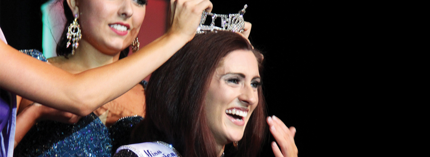 In this Saturday, June 18, 2016 photo, Miss Missouri 2016 Erin O'Flaherty is being crowned by Miss Missouri 2015 McKensie Garber and the new 2016 Miss Missouri's Outstanding Teen Christina Stratton, her arm seen, in Mexico, Mo. Missouri has its first openly gay Miss Missouri, and she will represent the state at the Miss America pageant later this year.
