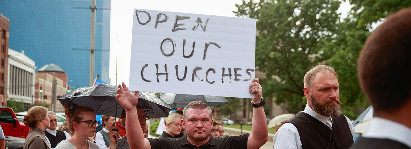 A protester holds a placard that says "Open Our Churches" during the We Will Not Comply anti mask rally in Indianapolis, Indiana on July 19, 2020.