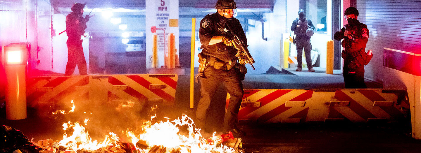 A Department of Homeland Security officer emerges from the Mark O. Hatfield United States Courthouse after demonstrators lit a fire on Sunday, Aug. 2, 2020, in Portland, Ore.
