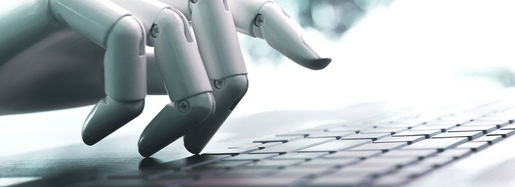 A robotic hand hovers over the keys of a laptop keyboard.