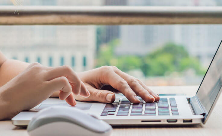 A woman types on a laptop computer.