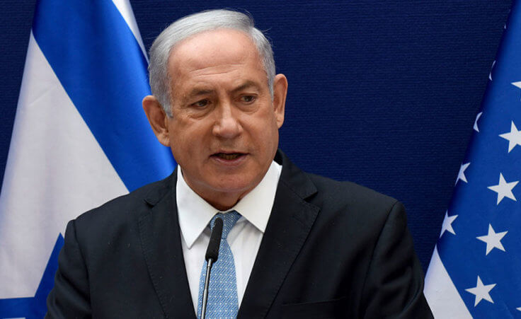 Israeli Prime Minister Benjamin Netanyahu stands in front of the flags of Israel and the United States