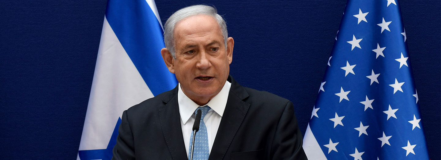 Israeli Prime Minister Benjamin Netanyahu stands in front of the flags of Israel and the United States