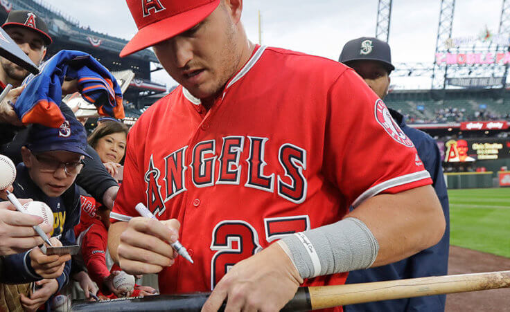 Los Angeles Angels center fielder Mike Trout autographs a bat