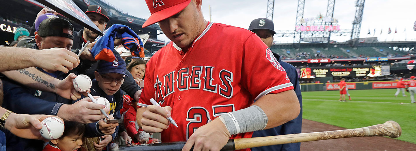 Los Angeles Angels center fielder Mike Trout autographs a bat