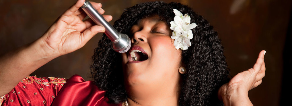 A Black female vocalist sings into a microphone