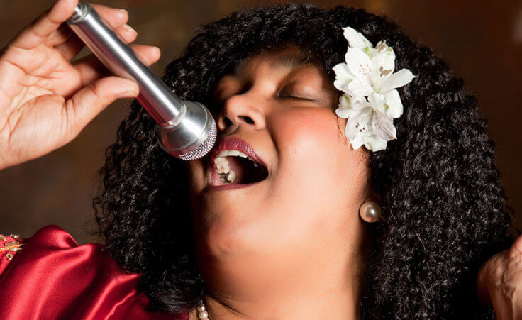 A Black female vocalist sings into a microphone