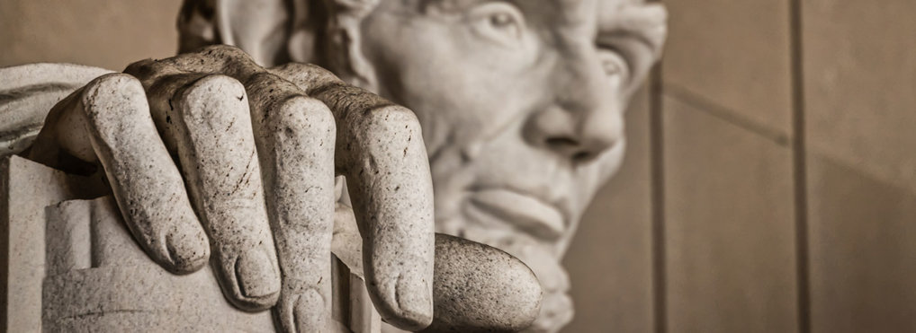 A closeup of a statue of Abraham Lincoln, focused on his hand with his face in the background