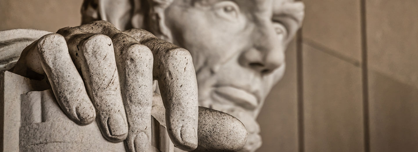 A closeup of a statue of Abraham Lincoln, focused on his hand with his face in the background