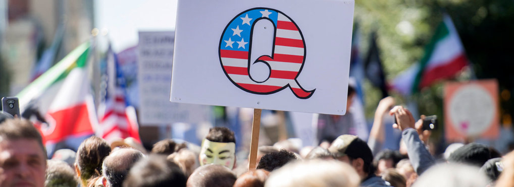Protestors hold up a QAnon sign.