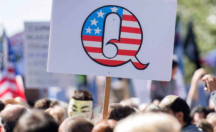 Protestors hold up a QAnon sign.