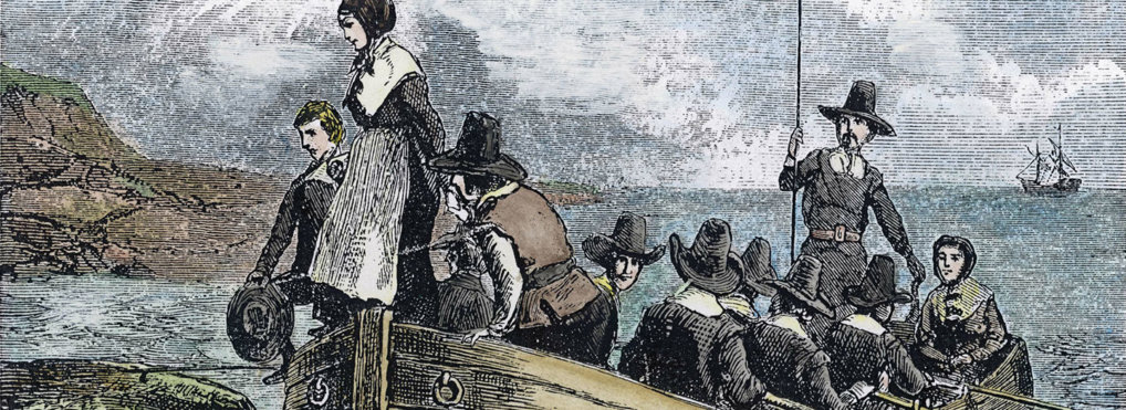 In a small row boat, with the Mayflower in the background, Pilgrims approach the shore.