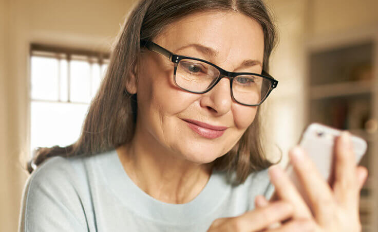 A senior adult woman looks at her cell phone