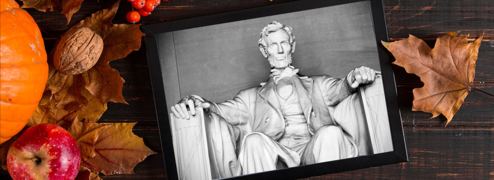 President Lincoln's photo appears on a tablet, sitting on a table, surrounded by pumpkins and fall foliage