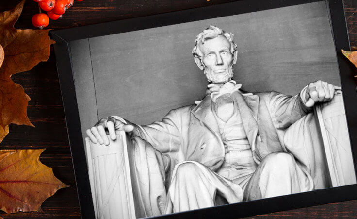 President Lincoln's photo appears on a tablet, sitting on a table, surrounded by pumpkins and fall foliage