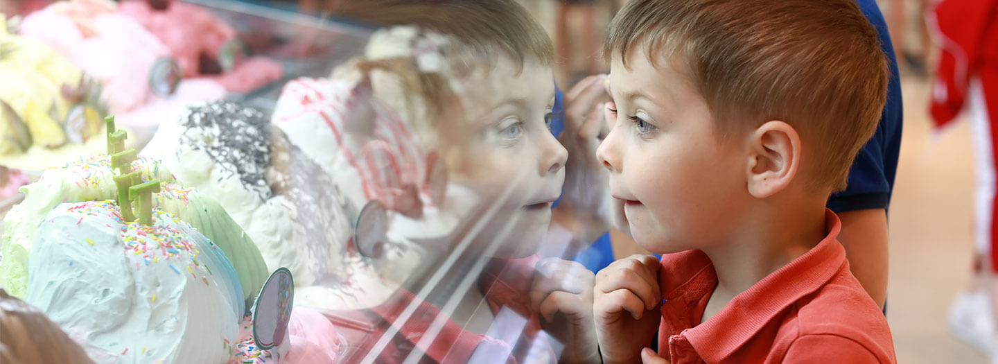 A boy looks at an assortment of ice cream behind a glass case