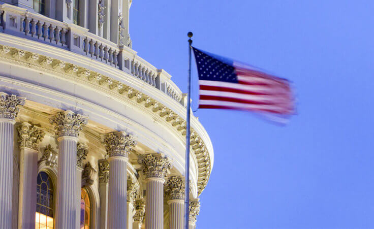 The American flag flaps in front of the US Capitol building