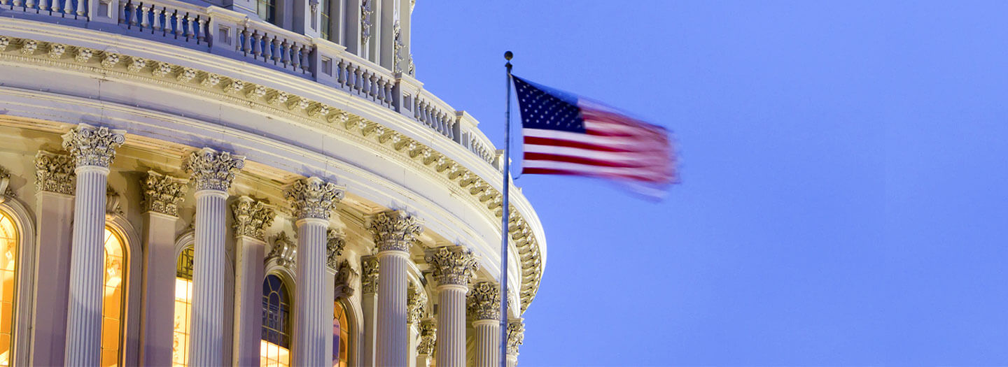 The American flag flaps in front of the US Capitol building