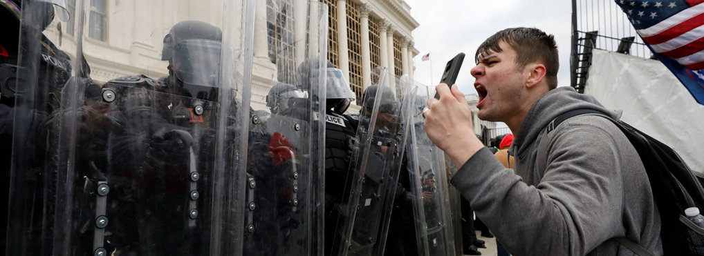 Police officers in riot gear stand guard while Trump supporters protest on the steps of U.S. Capitol in Washington on January 6, 2021.